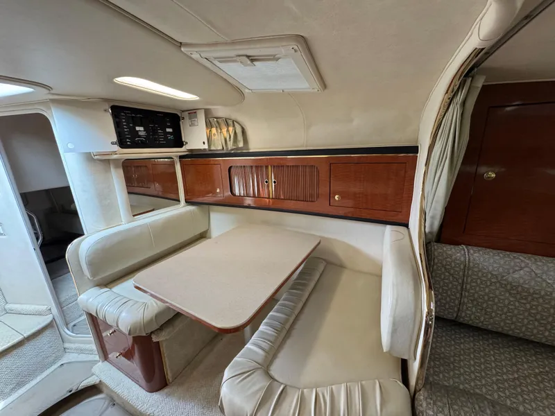 Slide: The Image of 2001 Sea Ray 290 Sundancer cabin interior with dining area and wooden cabinetry. - 23