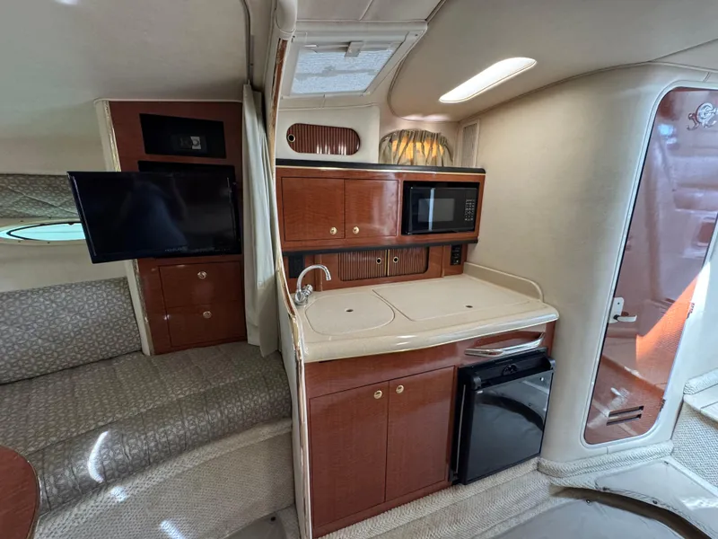 Slide: The Image of 2001 Sea Ray 290 Sundancer interior with kitchenette, TV, and seating area. - 24