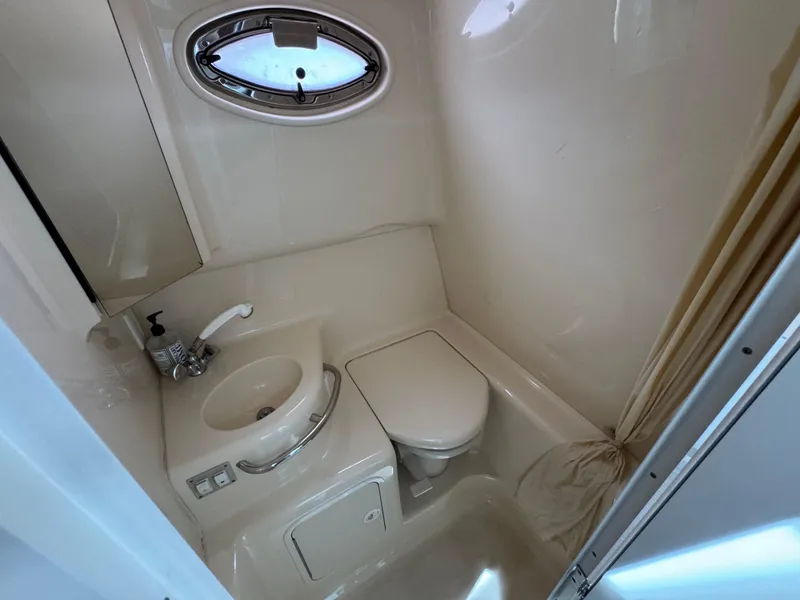 Slide: The Image of 2001 Sea Ray 290 Sundancer bathroom with sink, toilet, and porthole window. - 25