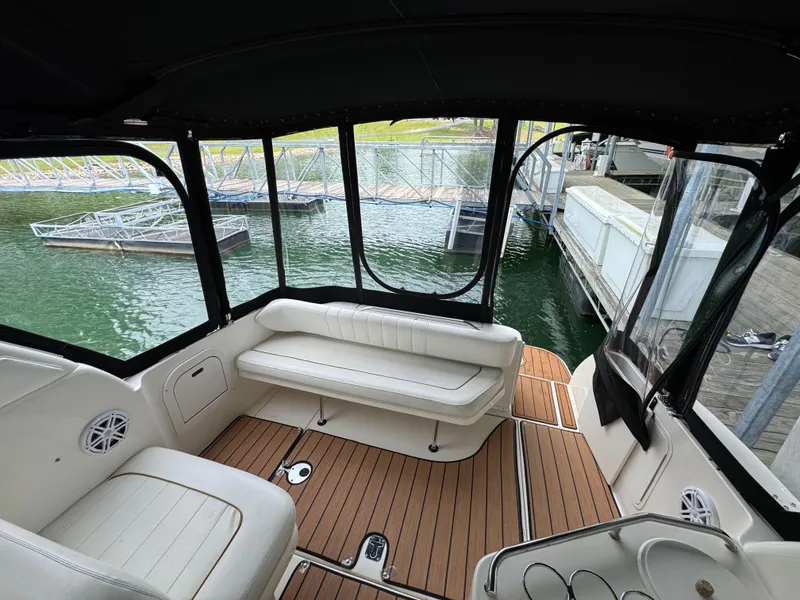 Slide: The Image of 2001 Sea Ray 290 Sundancer interior with white seating and wood flooring at a marina. - 28