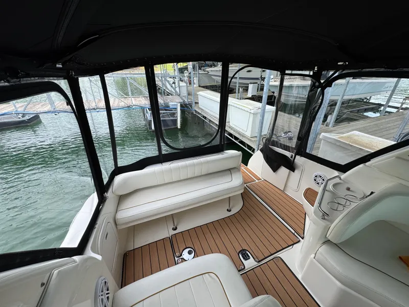 Slide: The Image of 2001 Sea Ray 290 Sundancer interior with white seating and wood flooring at a marina. - 29