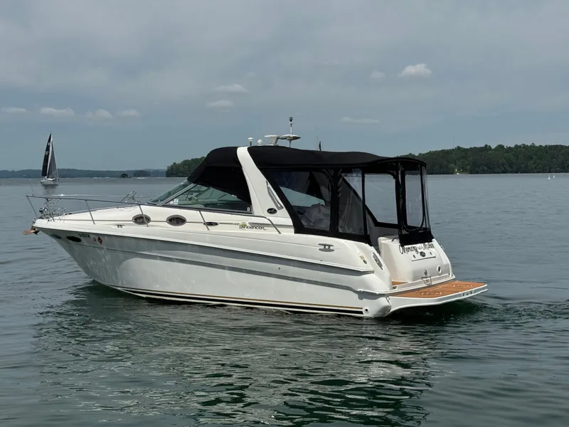 Slide: The Image of 2001 Sea Ray 290 Sundancer boat on calm water, featuring a sleek design and black canopy. - 4