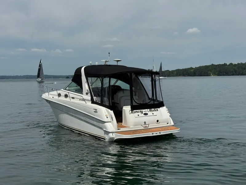Slide: The Image of 2001 Sea Ray 290 Sundancer boat on calm water with sailboats in the background. - 6