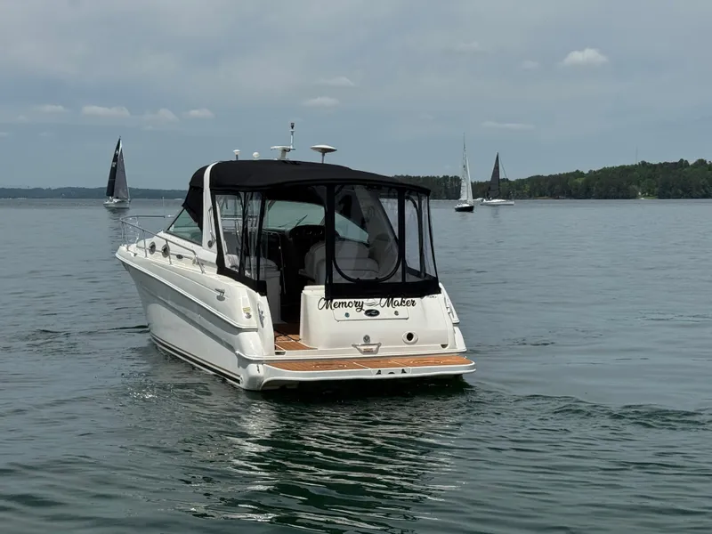 Slide: The Image of 2001 Sea Ray 290 Sundancer boat on calm water with sailboats in the background. - 7