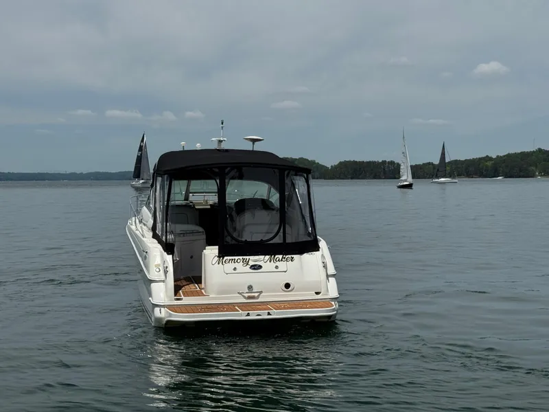 Slide: The Image of 2001 Sea Ray 290 Sundancer boat on calm water with sailboats in the background. - 8