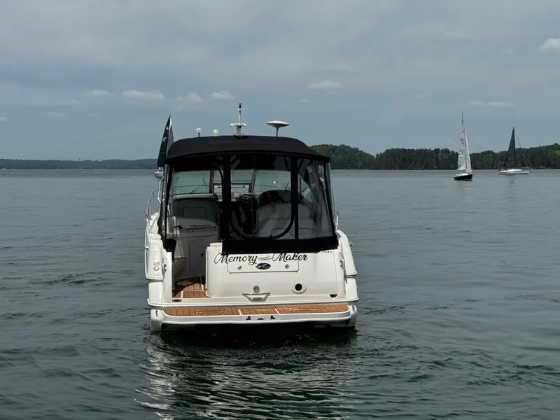 Slide: The Image of Sea Ray 290 Sundancer 2001 boat on calm water with sailboats in the background. - 9