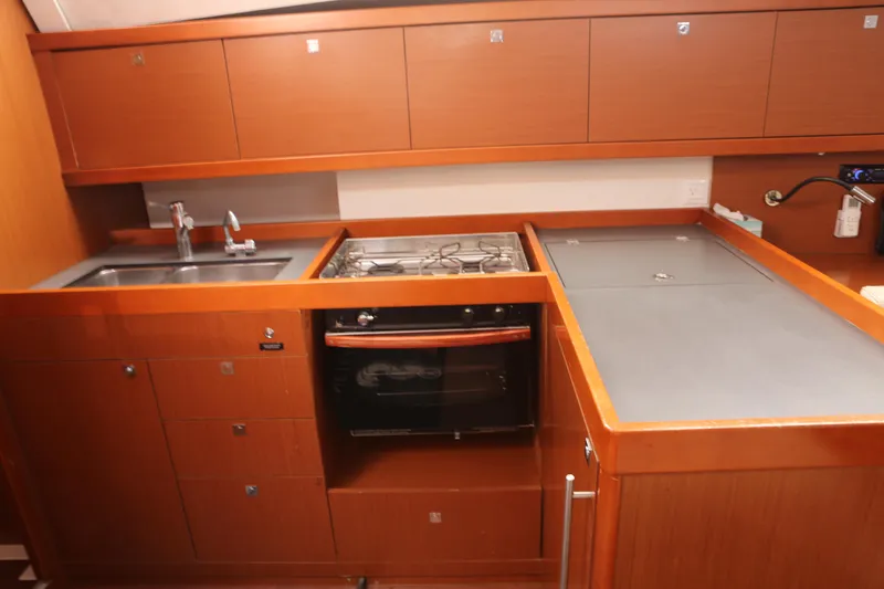 Slide: The Image of 2014 Beneteau Oceanis 41 yacht kitchen with wooden cabinetry, sink, stove, and oven. - 11