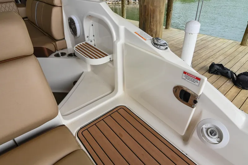 Slide: The Image of 2016 Sea Ray 270 Sundeck interior with tan seating and wood accents, dockside view. - 13