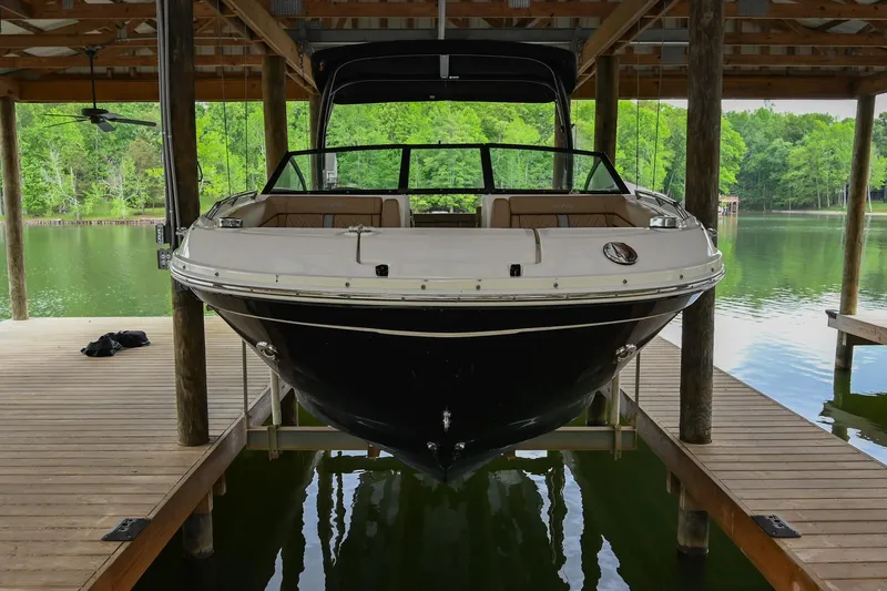 Slide: The Image of 2016 Sea Ray 270 Sundeck boat docked under a wooden shelter on a serene lake. - 2