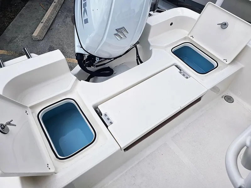 Slide: The Image of 2025 Pioneer 220 Bay Sport boat with open storage compartments and Suzuki outboard motor. - 10