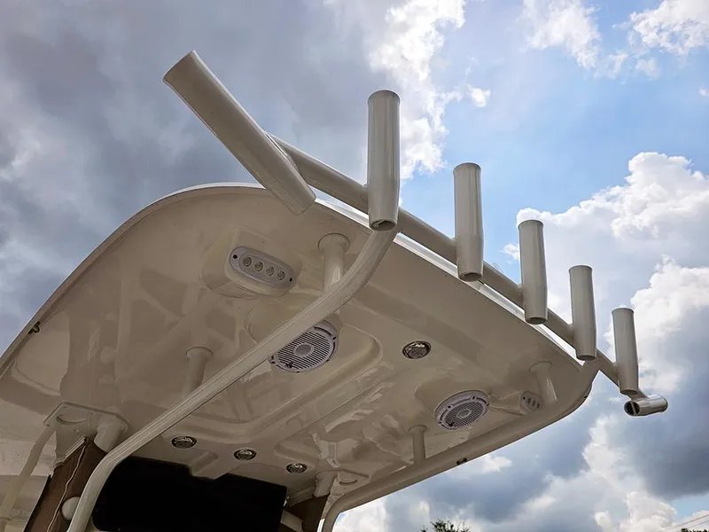 Slide: The Image of 2025 Pioneer 220 Bay Sport boat top with rod holders against cloudy sky. - 15