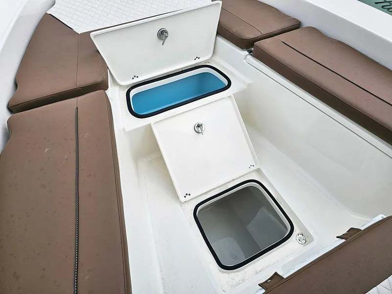 Slide: The Image of 2025 Pioneer 220 Bay Sport boat interior with open storage compartments and cushioned seating. - 18