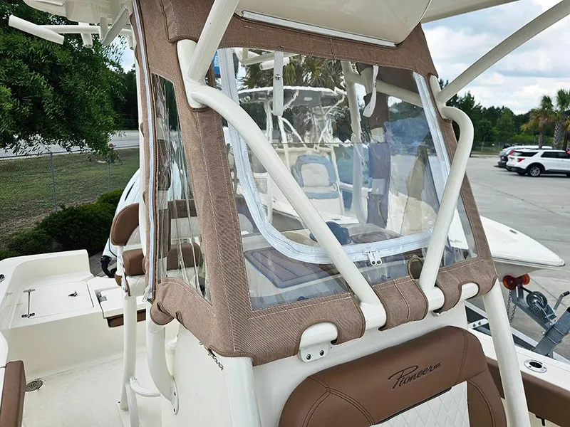 Slide: The Image of 2025 Pioneer 220 Bay Sport boat with protective canopy and seating, parked outdoors. - 21