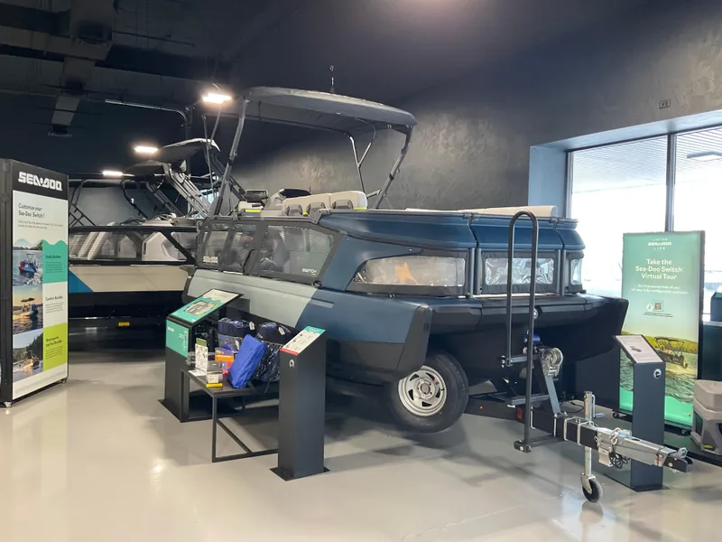 Slide: The Image of 2025 Sea-Doo Switch Cruise Limited 21 on display in showroom with promotional materials. - 1