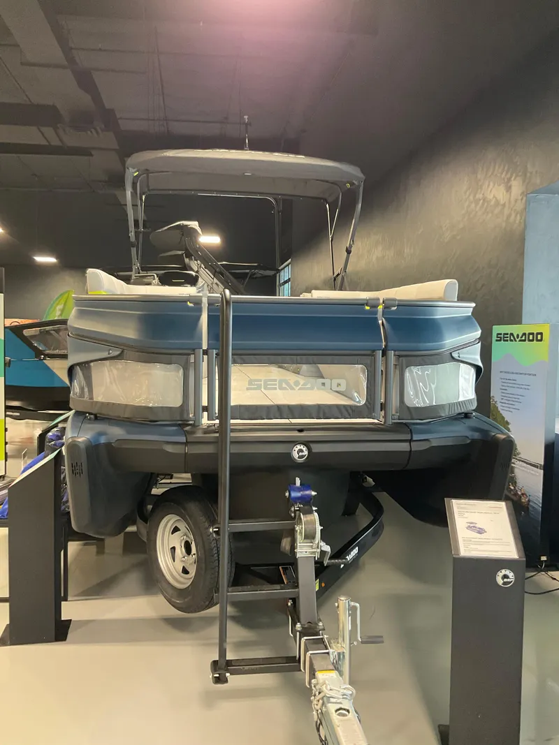 Slide: The Image of 2025 Sea-Doo Switch Cruise Limited 21 pontoon boat displayed indoors on a trailer. - 2