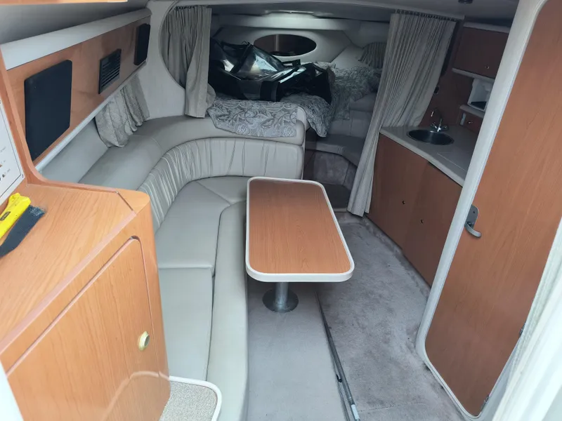 Slide: The Image of 2001 Regal Commodore 3260 cabin interior with seating, table, and sleeping area. - 8
