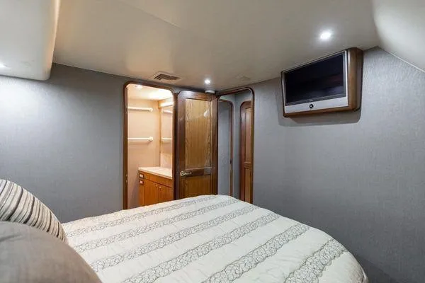 Slide: The Image of Interior of 2008 Ocean Yachts 46SS, featuring a cozy bedroom with TV and wooden accents. - 20
