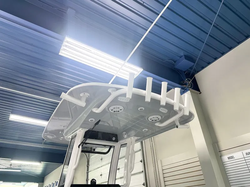 Slide: The Image of 2025 Sportsman Heritage 231 Center Console boat under blue ceiling with rod holders. - 11