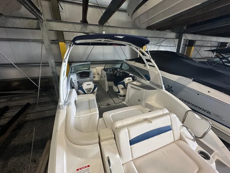Slide: The Image of 2018 Chaparral 244 Sunesta boat interior with seating and helm, stored indoors. - 18