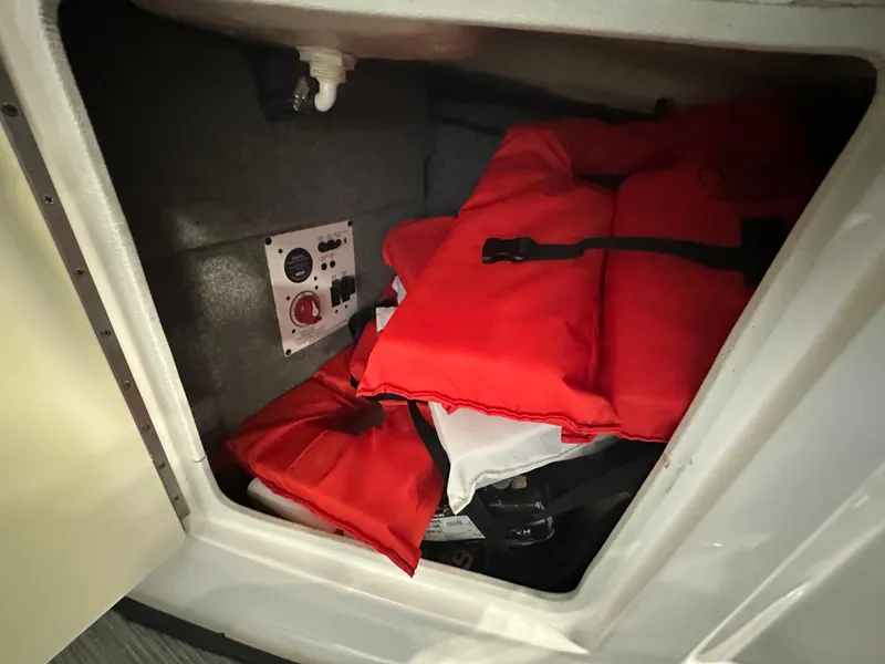 Slide: The Image of Storage compartment in 2018 Chaparral 244 Sunesta with red life jackets and control panel. - 26