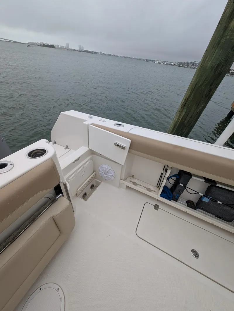 Slide: The Image of 2019 Sailfish 290cc boat interior, featuring seating and storage, docked by the water. - 12