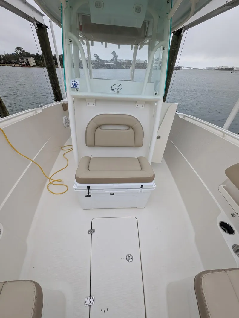 Slide: The Image of 2019 Sailfish 290cc boat interior with beige seating and storage, docked on a cloudy day. - 15