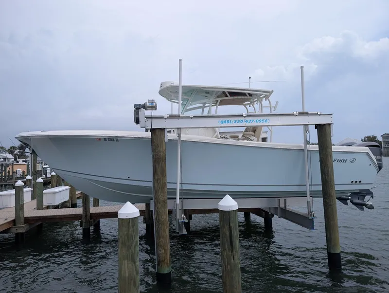 Slide: The Image of 2019 Sailfish 290cc boat on lift, docked by the water. - 3