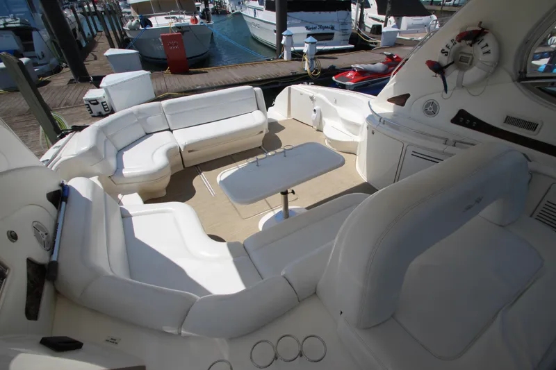 Slide: The Image of 2003 Sea Ray 550 Sundancer yacht interior with white seating and table, docked at marina. - 22