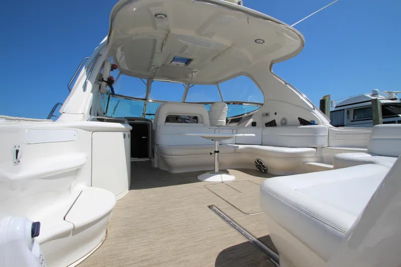 Slide: The Image of 2003 Sea Ray 550 Sundancer yacht interior with white seating and table under a clear blue sky. - 4