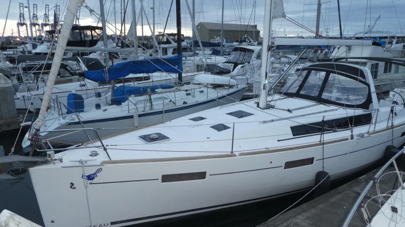 Slide: The Image of 2014 Beneteau Oceanis 41 sailboat docked in a marina, surrounded by other vessels. - 1