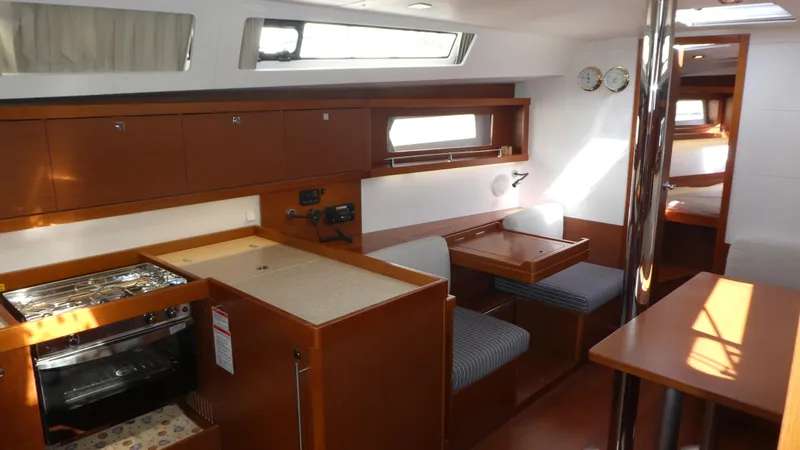 Slide: The Image of 2014 Beneteau Oceanis 41 interior with wood finish, dining area, and kitchen amenities. - 12