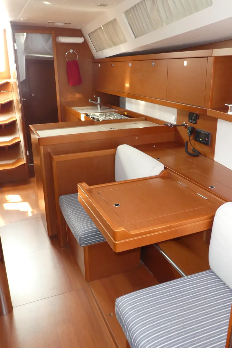 Slide: The Image of Interior of 2014 Beneteau Oceanis 41 sailboat with wood finish and compact kitchen area. - 13