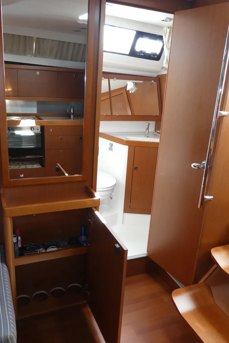 Slide: The Image of Interior of 2014 Beneteau Oceanis 41 sailboat, featuring wood cabinetry and compact kitchen area. - 26