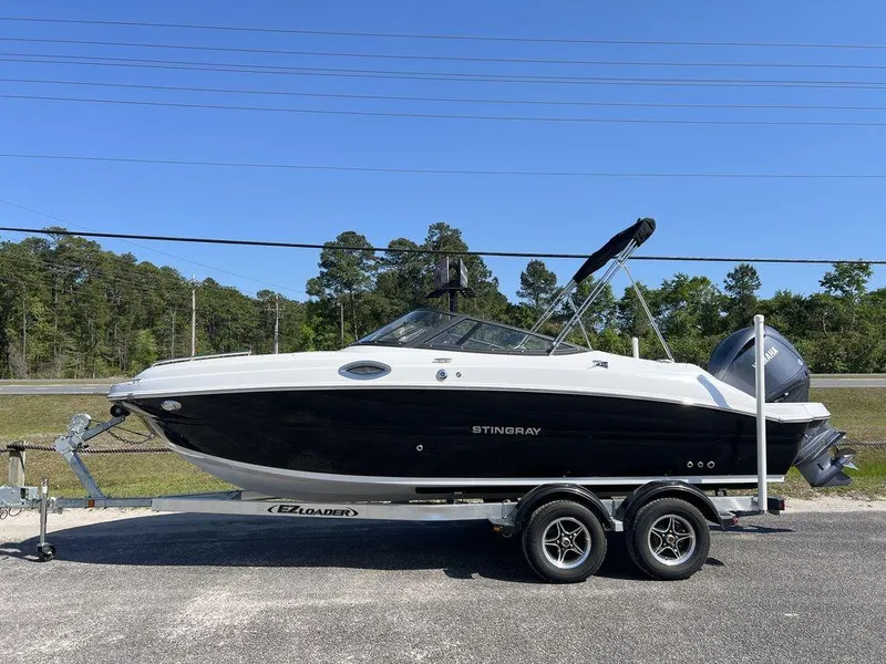 Slide: The Image of 2025 Stingray 211DC boat on trailer, black and white design, parked outdoors. - 1