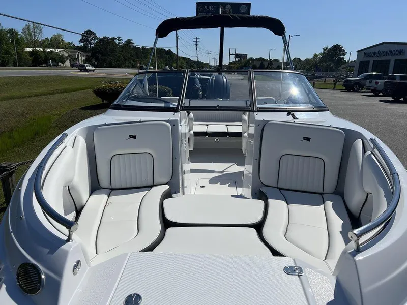 Slide: The Image of 2025 Stingray 211DC boat with white seating and open deck, parked outdoors. - 10