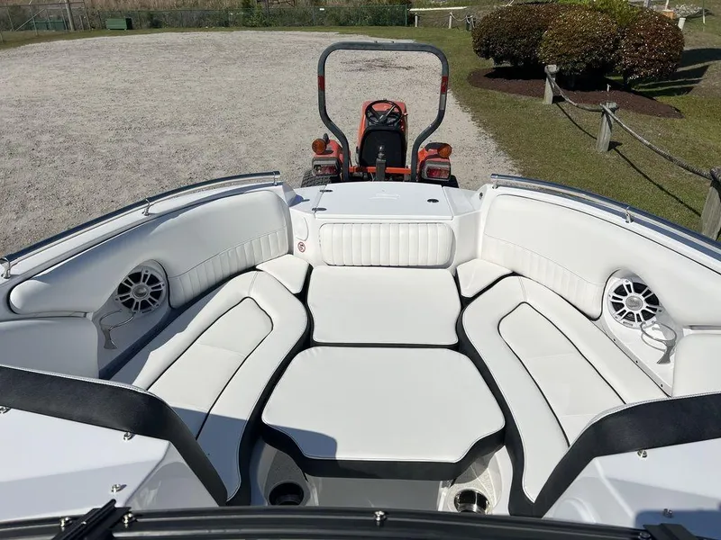 Slide: The Image of 2025 Stingray 211DC boat interior with white seating and speakers, parked on gravel. - 11