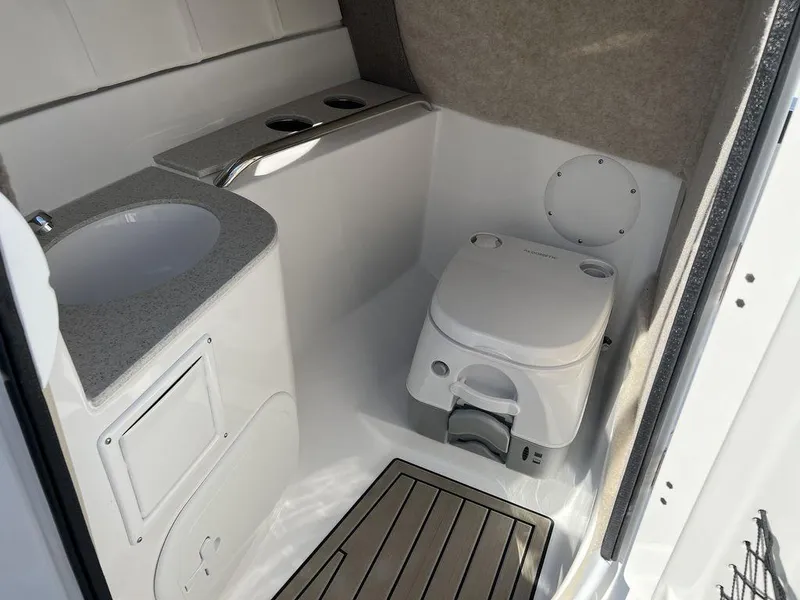 Slide: The Image of 2025 Stingray 211DC boat interior with compact bathroom, featuring a toilet and sink. - 17