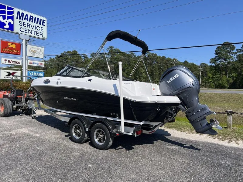 Slide: The Image of 2025 Stingray 211DC boat on trailer at Marine Service Center, featuring Yamaha outboard motor. - 2