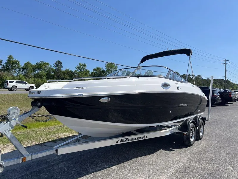 Slide: The Image of 2025 Stingray 211DC boat on trailer, parked outdoors under clear sky. - 3