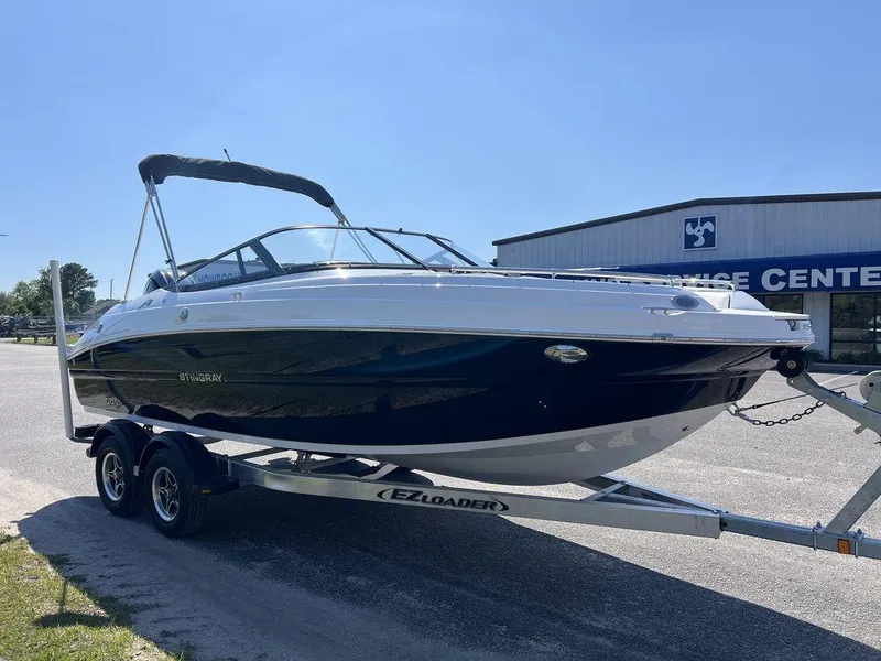 Slide: The Image of 2025 Stingray 211DC boat on trailer, parked outdoors near a service center. - 5