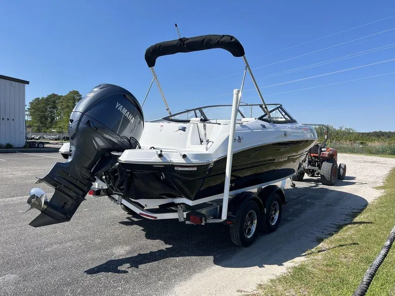 Slide: The Image of 2025 Stingray 211DC boat with Yamaha outboard motor on trailer, parked outdoors. - 6