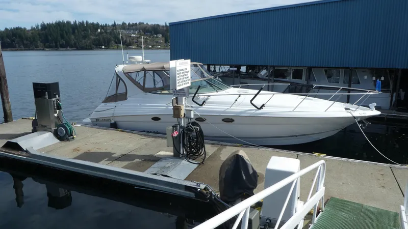 The Image of 2004 Larson 370 boat docked at marina with blue building in background. - 0