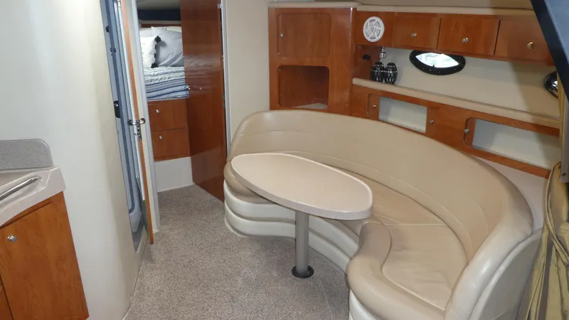 Slide: The Image of 2004 Larson 370 yacht interior with curved seating, wooden cabinets, and a small table. - 16