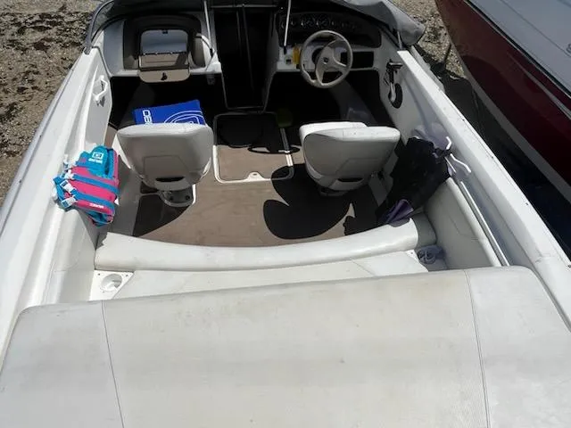 Slide: The Image of 2006 Larson 180 Bowrider SEI interior with seating and steering wheel, docked on sandy shore. - 7