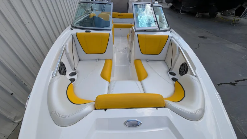 Slide: The Image of 2013 MasterCraft X2 boat interior with yellow and white seating, docked near a building. - 10