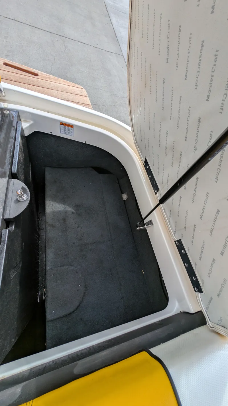 Slide: The Image of Open storage compartment in 2013 MasterCraft X2 boat, showing interior space and lid details. - 24
