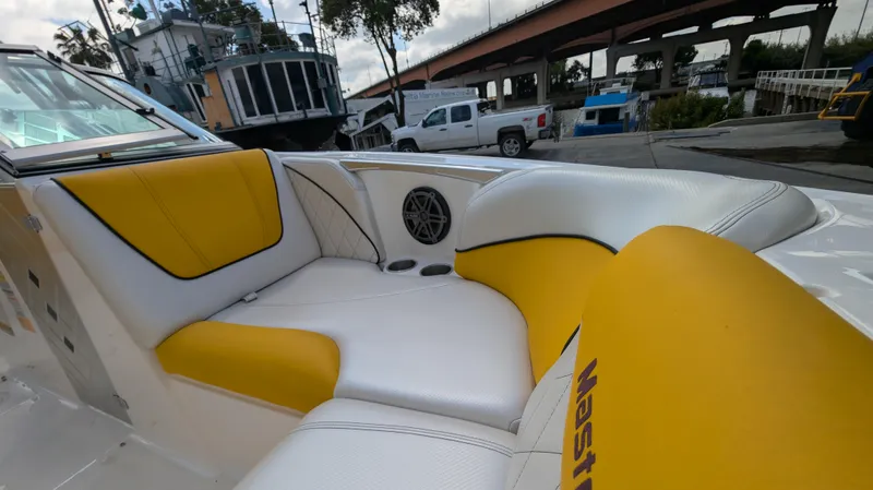 Slide: The Image of 2013 MasterCraft X2 boat interior with yellow and white seating, docked near a bridge. - 28