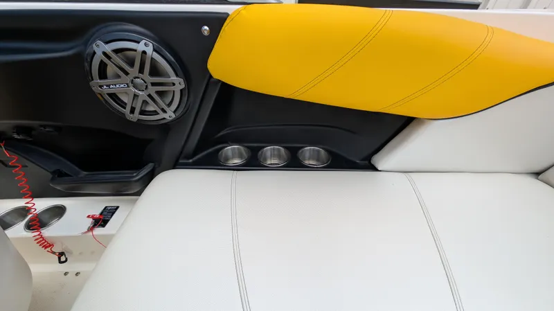 Slide: The Image of 2013 MasterCraft X2 boat interior with speaker, cup holders, and yellow-accented seating. - 29