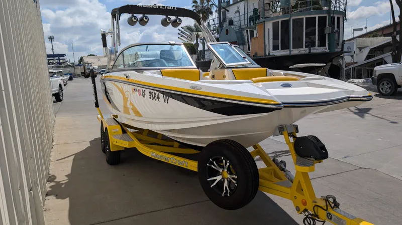 Slide: The Image of 2013 MasterCraft X2 boat on yellow trailer, parked outdoors on a sunny day. - 3