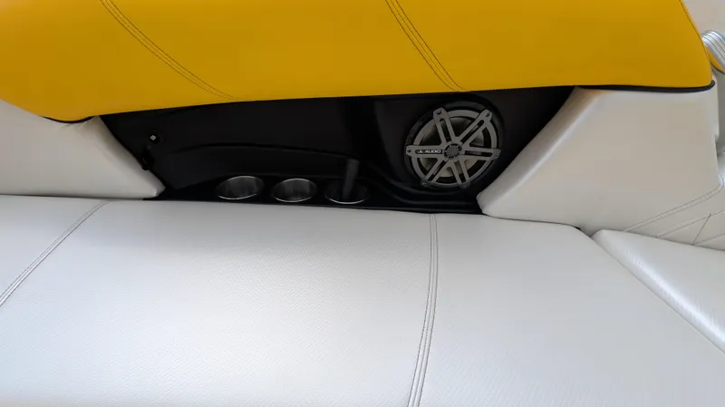 Slide: The Image of 2013 MasterCraft X2 boat interior with white and yellow upholstery, featuring a speaker and cup holders. - 30